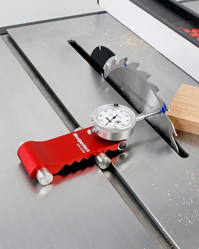 A dial indicator mounted in the miter slot measuring the lateral runout of a table saw blade
